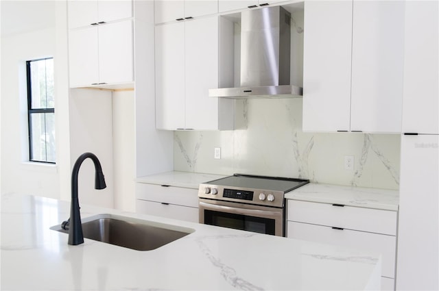 kitchen featuring tasteful backsplash, wall chimney range hood, modern cabinets, electric stove, and a sink