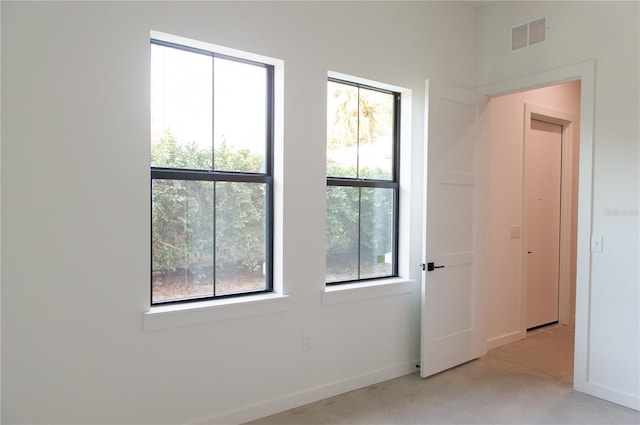 unfurnished room with baseboards, visible vents, and plenty of natural light