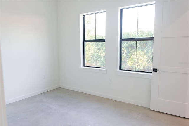 unfurnished room featuring concrete flooring and baseboards
