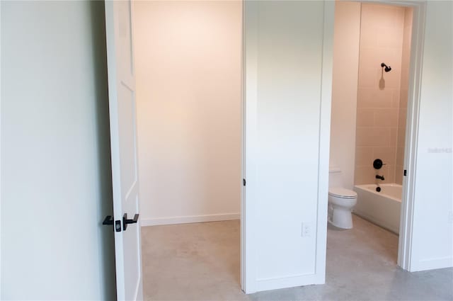 bathroom featuring toilet, concrete flooring, baseboards, and  shower combination