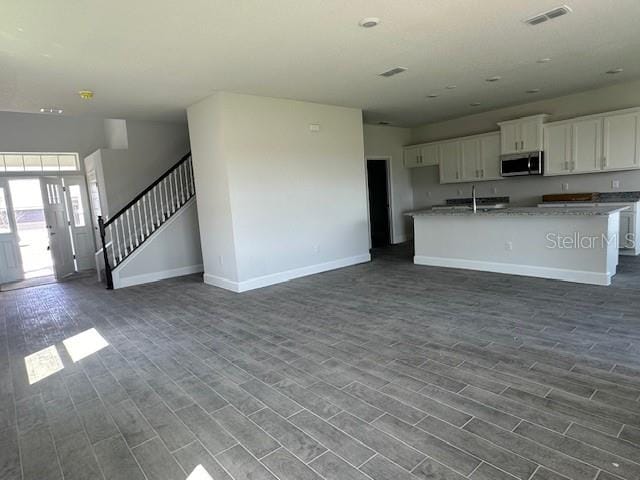 7002 162nd Pl E, Parrish, FL 34219 - unfurnished living room featuring visible vents, baseboards, and dark wood-style floors