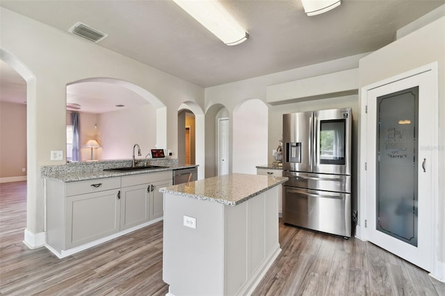 kitchen with white cabinets, sink, appliances with stainless steel finishes, and light wood-type flooring