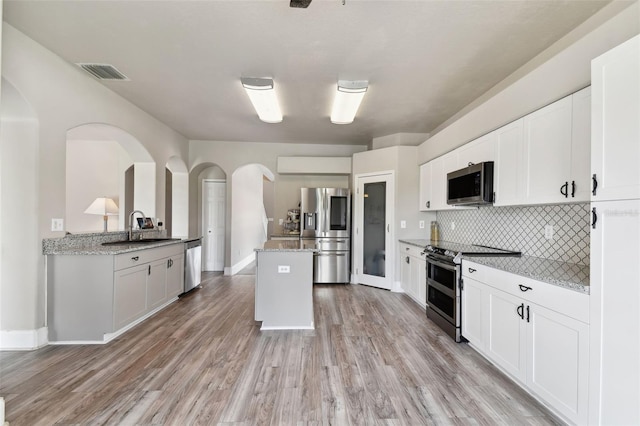 kitchen with white cabinets, tasteful backsplash, stainless steel appliances, and light wood-type flooring