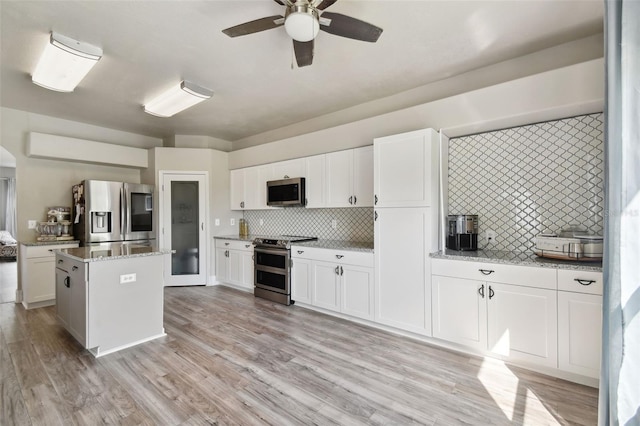 kitchen with ceiling fan, a kitchen island, white cabinets, backsplash, and stainless steel appliances