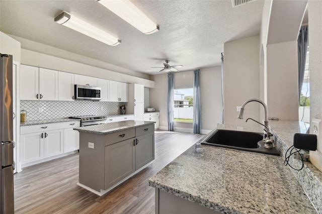 kitchen with appliances with stainless steel finishes, backsplash, ceiling fan, white cabinetry, and sink