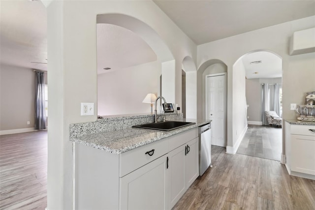 kitchen with sink, light wood-type flooring, white cabinetry, and light stone countertops