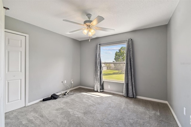 carpeted empty room featuring ceiling fan and a textured ceiling