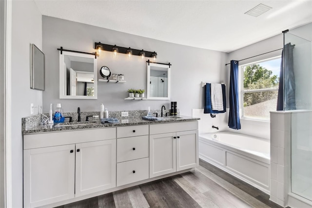 bathroom featuring independent shower and bath, hardwood / wood-style floors, and double sink vanity