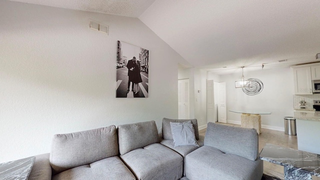 living room with light tile floors, vaulted ceiling, and a notable chandelier