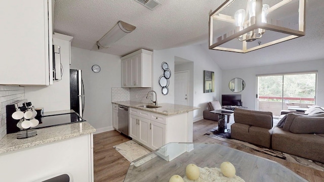 kitchen with light wood-type flooring, white cabinetry, light stone countertops, and lofted ceiling