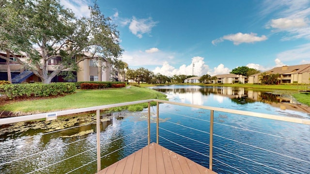 view of dock featuring a water view and a yard