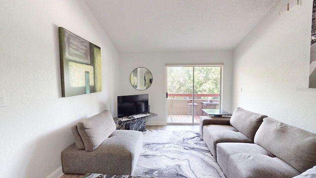 living room with a textured ceiling, vaulted ceiling, and light hardwood / wood-style flooring