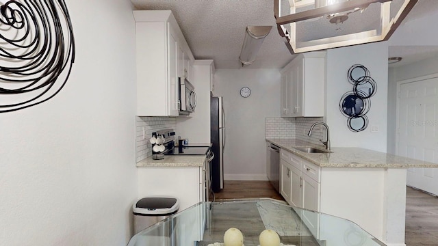 kitchen with backsplash, white cabinets, appliances with stainless steel finishes, and sink