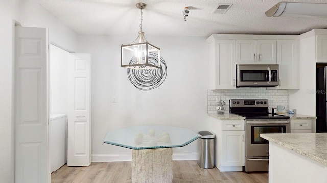 kitchen with light hardwood / wood-style flooring, decorative light fixtures, appliances with stainless steel finishes, and white cabinetry