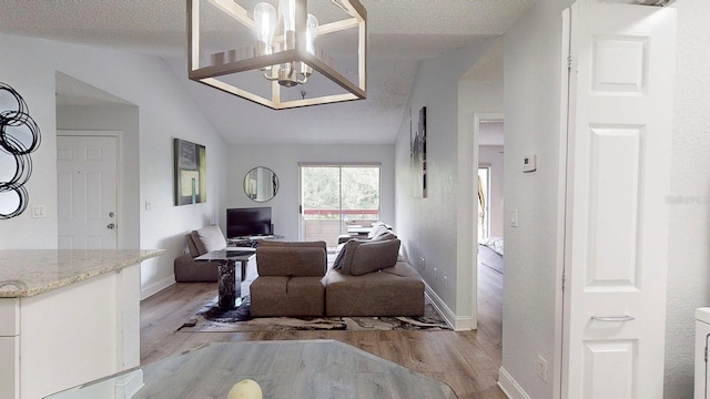 interior space with an inviting chandelier, lofted ceiling, a textured ceiling, and light hardwood / wood-style floors