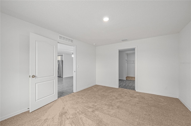 empty room with a textured ceiling and carpet flooring