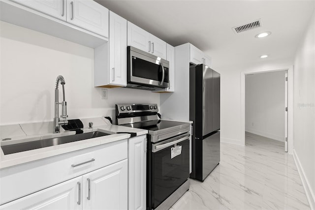 kitchen featuring appliances with stainless steel finishes, white cabinetry, and sink