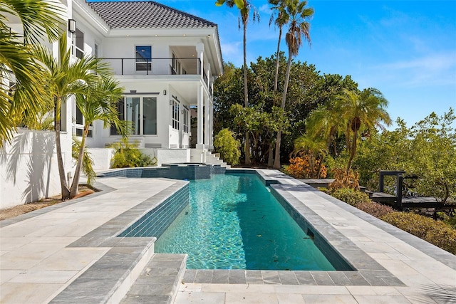 back of property with a balcony, a patio, and a fenced in pool