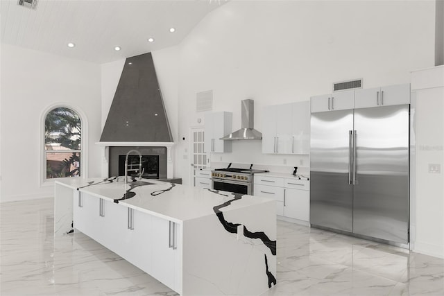 kitchen featuring wall chimney exhaust hood, a spacious island, high vaulted ceiling, and premium appliances