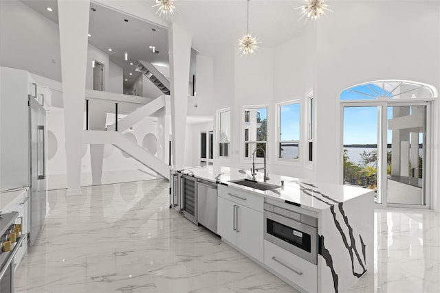 kitchen with pendant lighting, a towering ceiling, appliances with stainless steel finishes, and white cabinetry