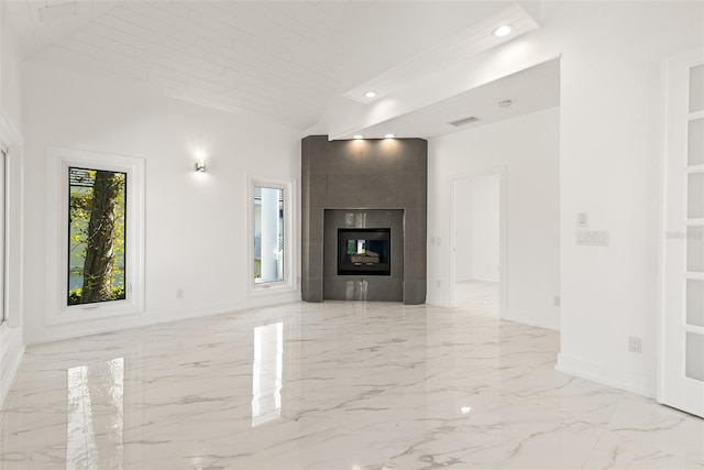 unfurnished living room featuring a tiled fireplace and high vaulted ceiling