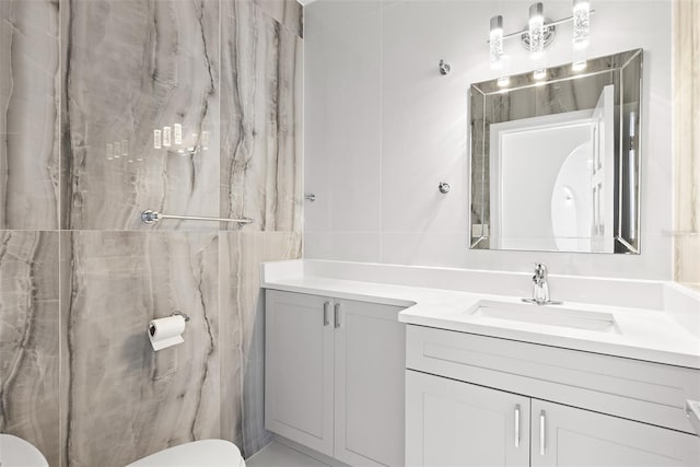 bathroom with vanity, toilet, and tile walls