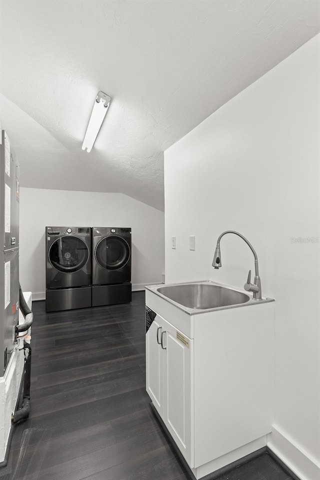 kitchen with washing machine and clothes dryer, dark wood-type flooring, sink, white cabinetry, and lofted ceiling