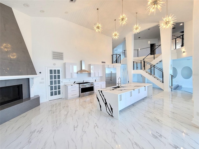 kitchen with decorative light fixtures, white cabinetry, a large island, premium appliances, and high vaulted ceiling