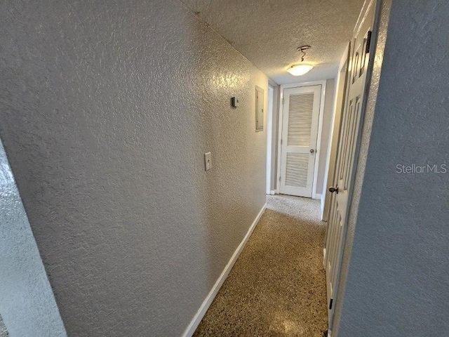 hallway with light carpet and a textured ceiling