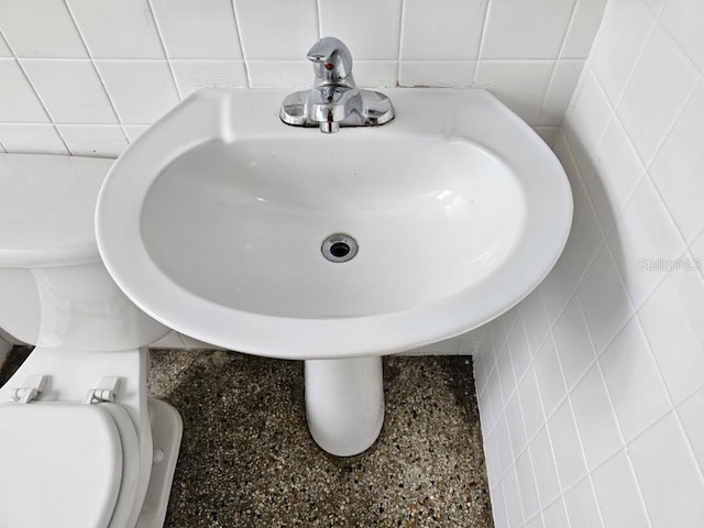 bathroom featuring tile walls and toilet