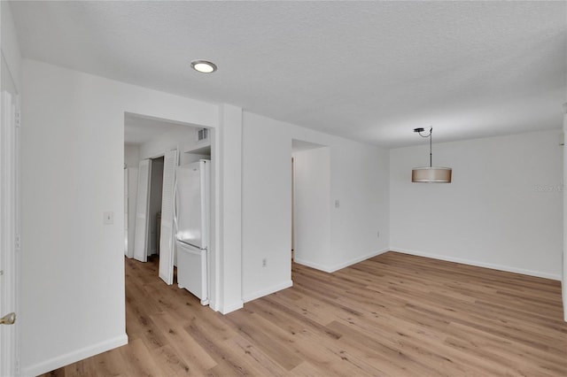 spare room featuring a textured ceiling and light hardwood / wood-style flooring