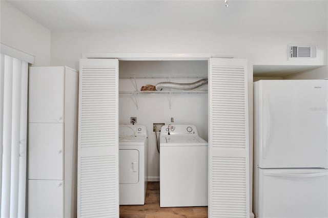 washroom with washer hookup, hardwood / wood-style floors, and washing machine and dryer