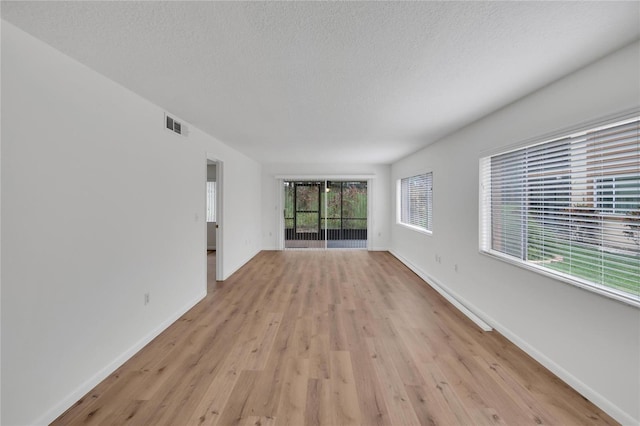 empty room with a textured ceiling and light wood-type flooring