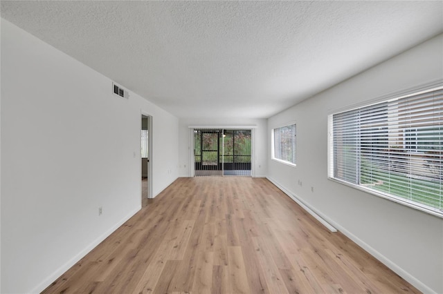 unfurnished room with a textured ceiling and light hardwood / wood-style flooring