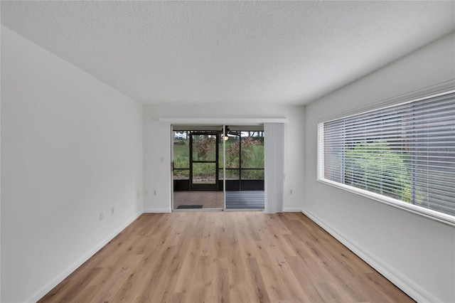 unfurnished room featuring an inviting chandelier, light hardwood / wood-style floors, and a textured ceiling