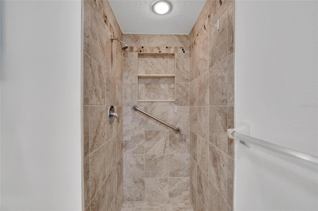 interior details featuring a tile shower and a textured ceiling