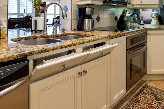 kitchen with dishwasher, oven, tasteful backsplash, black electric cooktop, and sink