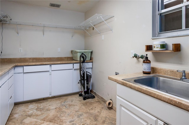 kitchen with white cabinetry, sink, and light tile flooring