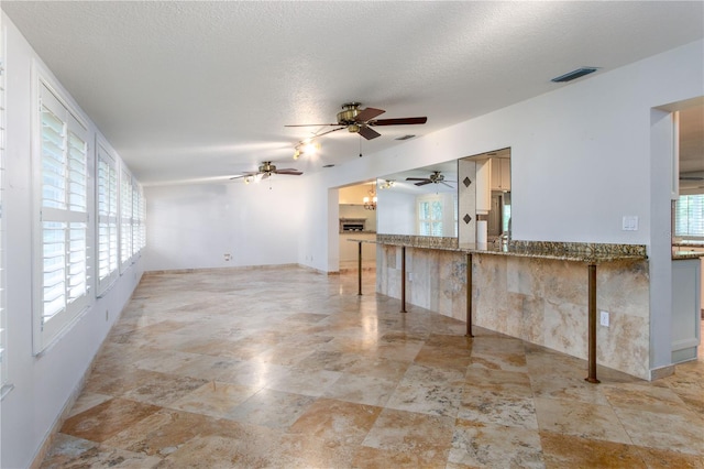 kitchen with kitchen peninsula, a textured ceiling, ceiling fan, and light tile floors