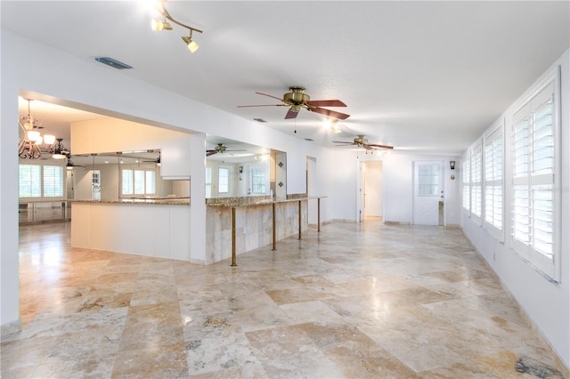 tiled empty room with ceiling fan with notable chandelier and track lighting