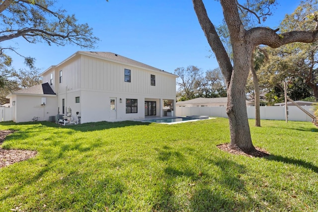 back of house featuring a fenced backyard, a fenced in pool, and a lawn