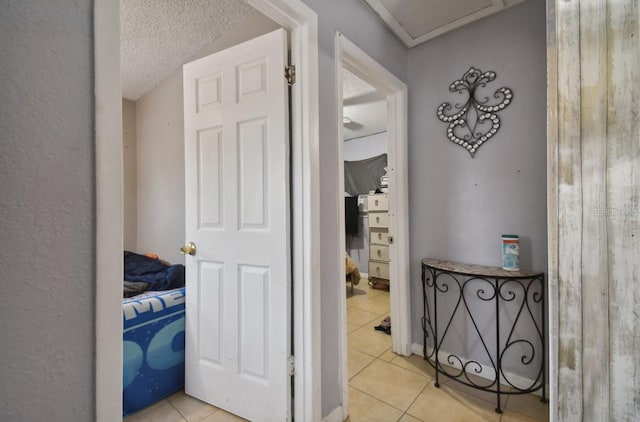 corridor with light tile patterned flooring and a textured ceiling