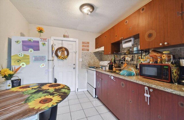 kitchen with a textured ceiling, decorative backsplash, light tile patterned flooring, and white appliances