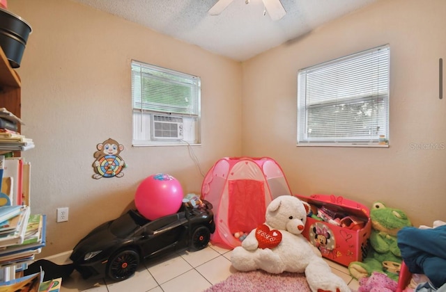 recreation room with ceiling fan, light tile patterned floors, and a textured ceiling