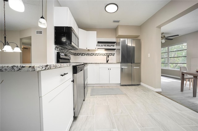 kitchen featuring pendant lighting, white cabinets, appliances with stainless steel finishes, tasteful backsplash, and ceiling fan with notable chandelier