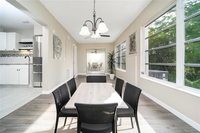 dining area featuring dark hardwood / wood-style floors, a healthy amount of sunlight, and ceiling fan with notable chandelier