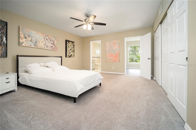 carpeted bedroom featuring a closet, ceiling fan, and ensuite bathroom