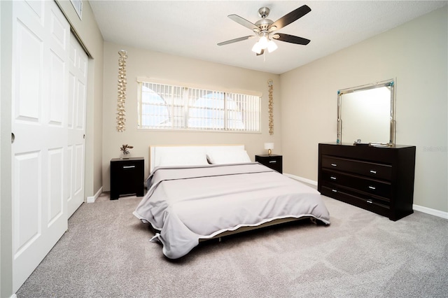 bedroom with a closet, ceiling fan, and light colored carpet