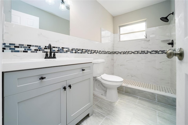 bathroom featuring toilet, vanity, tile walls, tile flooring, and a tile shower