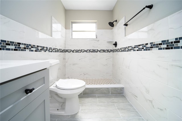 bathroom with tile walls, toilet, tiled shower, tile floors, and vanity